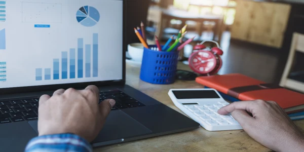 Business man using calculator to review balance sheet annual with holding pen and using laptop computer
